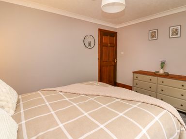 A bedroom with a bed a wooden door a dresser with a vase and pictures on the wall at Pondarosa in Newbridge-On-Wye