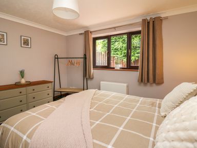 A bedroom with a bed a dresser and a window with curtains at Pondarosa in Newbridge-On-Wye