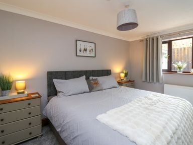 A bedroom with a large bed two bedside tables table lamps and a window with curtains at Pondarosa in Newbridge-On-Wye