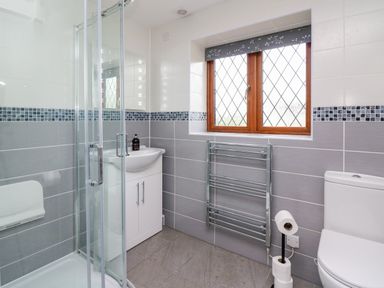 A bathroom with a corner shower enclosure sink with cabinet towel radiator window and toilet at Pondarosa in Newbridge-On-Wye