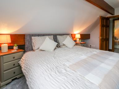 A bedroom with a bed between two nightstands with lamps and decorative pillows at Pondarosa in Newbridge-On-Wye