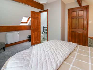 A bedroom with a bed and two wooden doors one leading to a bathroom at Pondarosa in Newbridge-On-Wye