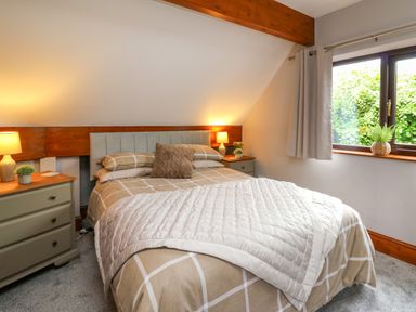 A bedroom with a bed lamp bedside tables and a window with curtains at Pondarosa Newbridge-On-Wye