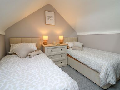 A bedroom with two single beds a chest of drawers with two lamps and a framed quote on the wall at Pondarosa in Newbridge-On-Wye
