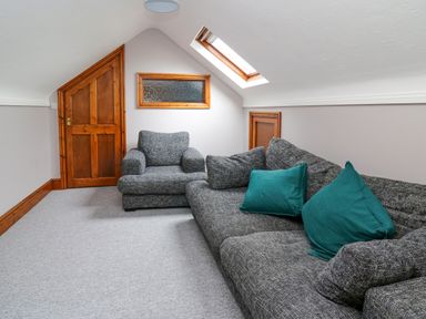 A sitting area with a gray sofa and armchair under a skylight window at Pondarosa in Newbridge-On-Wye
