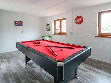 A pool room with a red pool table and two windows at Pondarosa in Newbridge-On-Wye