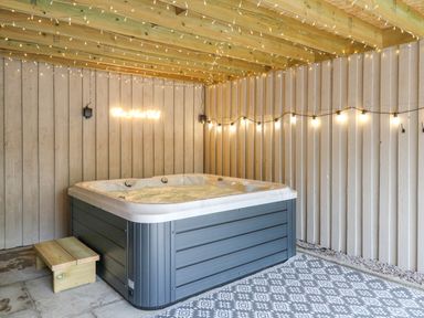 An indoor hot tub with wooden steps string lights on ceiling and walls at Pondarosa in Newbridge-On-Wye
