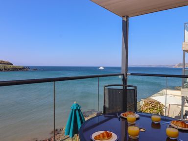 A balcony with a table set with croissants and glasses of orange juice overlooking the ocean at 14 Burgh Island Causeway in Bigbury-On-Sea