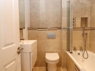 A bathroom with a white door sink toilet and bathtub with shower at 14 Burgh Island Causeway in Bigbury-On-Sea