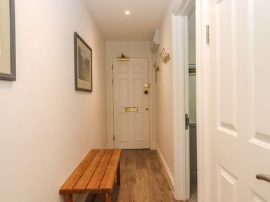 A narrow hallway with a wooden bench and hooks on the wall at 14 Burgh Island Causeway in Bigbury-On-Sea