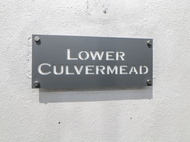 A metal sign with the text Lower Culvermead mounted on a white textured wall at Lower Culvermead in Chaddlehanger near Tavistock