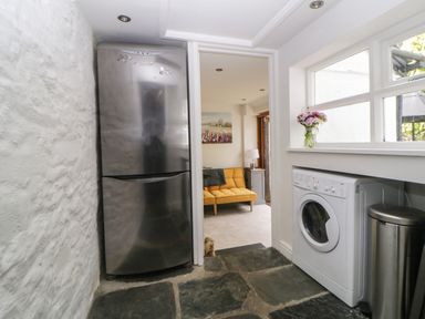 A kitchen area with a stainless steel fridge a washing machine and a window with flowers on the sill at Lower Culvermead in Chaddlehanger near Tavistock
