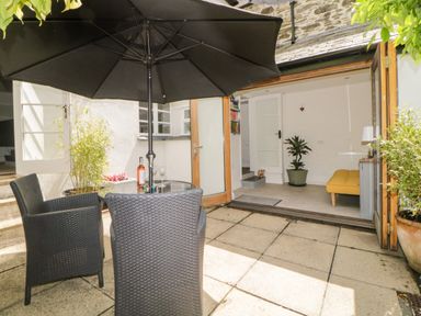 A patio area with a table and two chairs under a black umbrella at Lower Culvermead in Chaddlehanger near Tavistock