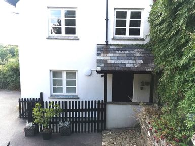 A white two-story house with black picket fence and potted plants at the entrance at Lower Culvermead in Chaddlehanger near Tavistock