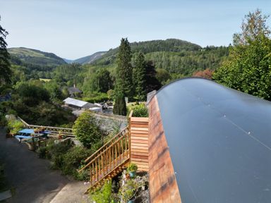 A view of green hills and trees with a wooden staircase and blue picnic table at The Kites Nest in Pont-rhyd-y-groes near Pontrhydfendigaid Snowdonia