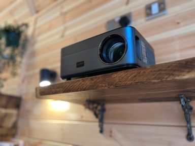 A projector on a wooden shelf with a light and power socket on a wooden wall at The Kites Nest in Pont-rhyd-y-groes near Pontrhydfendigaid Snowdonia