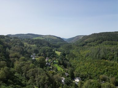 A valley with houses among trees and hills under a clear sky at The Kites Nest in Pont-rhyd-y-groes near Pontrhydfendigaid Snowdonia