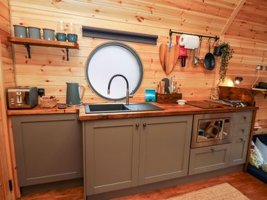 A kitchen with a round window gray cabinets wooden countertop and various kitchen utensils at The Kites Nest Pont-rhyd-y-groes near Pontrhydfendigaid Snowdonia