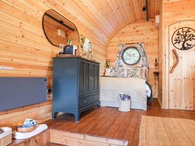 A wooden bedroom with a bed a dark blue cabinet a round window and a door with a tree design at The Kites Nest in Pont-rhyd-y-groes near Pontrhydfendigaid Snowdonia