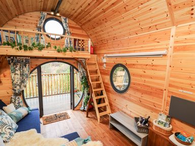 A wooden cabin interior with a staircase leading to a loft and round windows at The Kites Nest in Pont-rhyd-y-groes near Pontrhydfendigaid Snowdonia