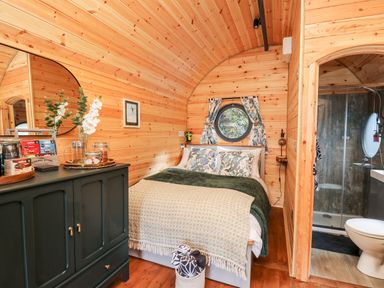 A bedroom with a bed and a green cabinet next to a bathroom at The Kites Nest in Pont-rhyd-y-groes near Pontrhydfendigaid Snowdonia