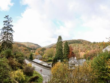 A winding road with houses and trees in a wooded valley at The Kites Nest in Pont-rhyd-y-groes near Pontrhydfendigaid Snowdonia