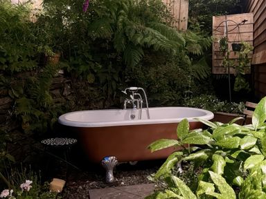 An outdoor bathtub surrounded by plants and greenery at The Kites Nest in Pont-rhyd-y-groes near Pontrhydfendigaid Snowdonia