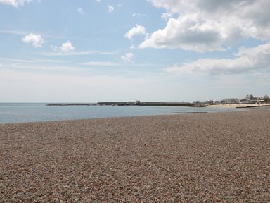 A pebble beach with a harbor and buildings in the distance at Teal House in Lyme Regis