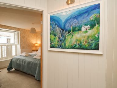 A bedroom with a bed and towels next to a window and a painting on the wall at Tan y Craig in Solva