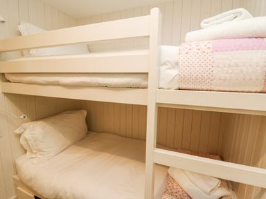 A bunk bed with white bedding and folded towels on the top bunk at Tan y Craig in Solva