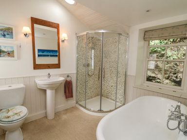 A bathroom with a toilet sink mirror shower bathtub and window at Tan y Craig in Solva