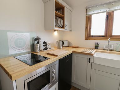 A kitchen with a microwave oven stovetop utensils kettle and toaster at Tan Y Castell Shepherds Hut in Llangollen