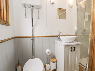 A bathroom with a high level toilet a vanity unit with sink a shower and toilet accessories at Tan Y Castell Shepherds Hut in Llangollen