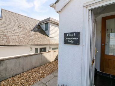 An entrance door open to a flat with a sign on the wall saying Flat 1 Camperdown Lodge in Salcombe