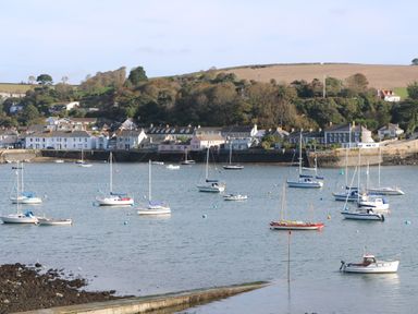 A harbor with multiple sailboats and motorboats anchored near a village with houses and trees at Primrose Cottage in Goldenbank near Falmouth