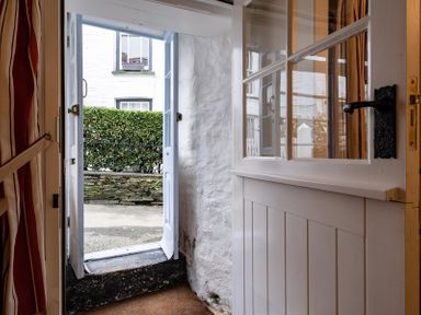 An open door leading outside with a small step and a hedge visible at St Samson in Port Isaac