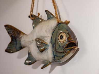 A ceramic fish hanging on a wall by a rope at St Samson in Port Isaac