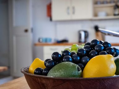 A kitchen with a wooden bowl of lemons grapes and avocado on a countertop at St Samson in Port Isaac