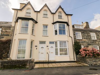 Two attached cream colored houses with white doors and bay windows at Bay View in Criccieth