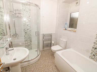 A bathroom with a sink, shower, toilet, and bathtub at Bay View in Criccieth