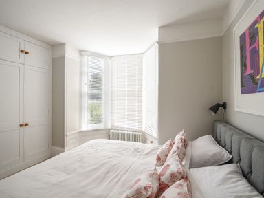 A bedroom with a bed white bedding built in wardrobes and a bay window at Coastal View in Lyme Regis