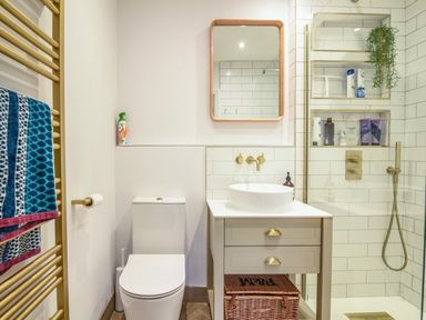 A bathroom with a toilet sink vanity mirror towel rail and a glass shower at Coastal View in Lyme Regis