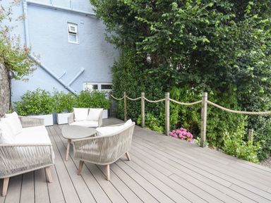 An outdoor deck with modern outdoor furniture and plants along a rope fence at Coastal View in Lyme Regis