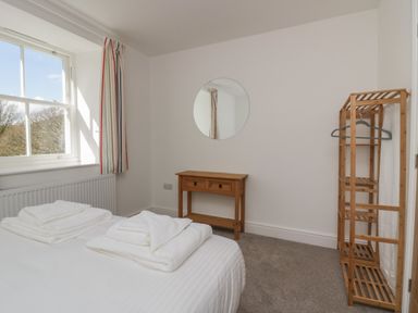 A bedroom with a bed with towels on it a window with striped curtains a wooden console table and a wooden shelving unit at Dalegarth Hall Farm Cottage 1 Boot near Eskdale Green