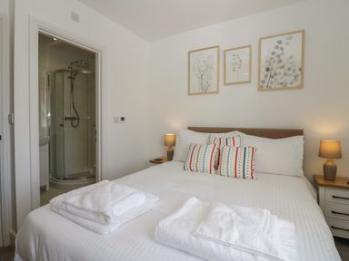 A bedroom with a bed pillows bedside tables lamps folded towels and an en suite bathroom with a shower at Dalegarth Hall Farm Cottage 1 Boot near Eskdale Green
