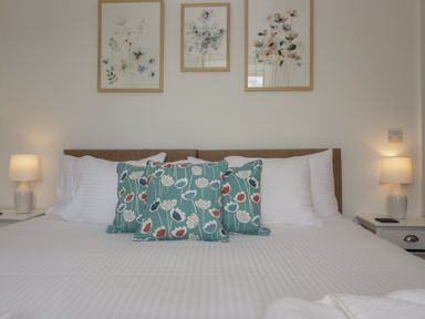 A bedroom with a bed with white bedding blue floral pillows two bedside tables and lamps at Dalegarth Hall Farm Cottage 1 Boot near Eskdale Green
