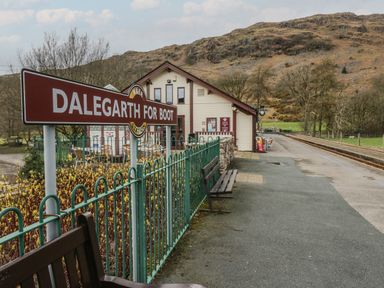 A train station platform with benches and a sign reading Dalgarth for Boot with hills in the background at Dalegarth Hall Farm Cottage 1 Boot near Eskdale Green