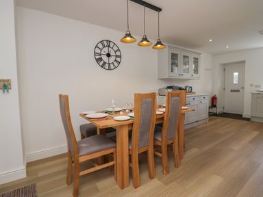 A dining area with a wooden table and six chairs set with plates and glasses at Dalegarth Hall Farm Cottage 1 Boot near Eskdale Green