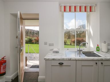 A kitchen sink with a window above it and an open door leading outside at Dalegarth Hall Farm Cottage 1 Boot near Eskdale Green