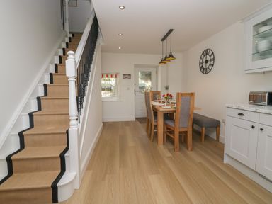 A dining area with wooden chairs and table set for dinner beside a staircase with carpet runner at Dalegarth Hall Farm Cottage 1 Boot near Eskdale Green